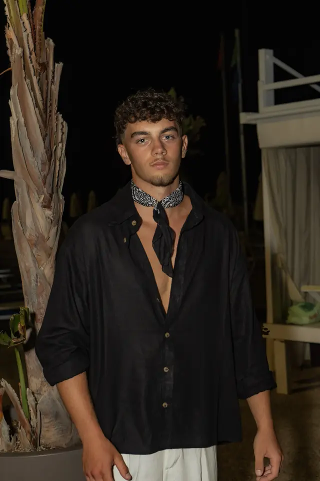 Ragazzo in camicia nera in lino e bandana sul lungomare