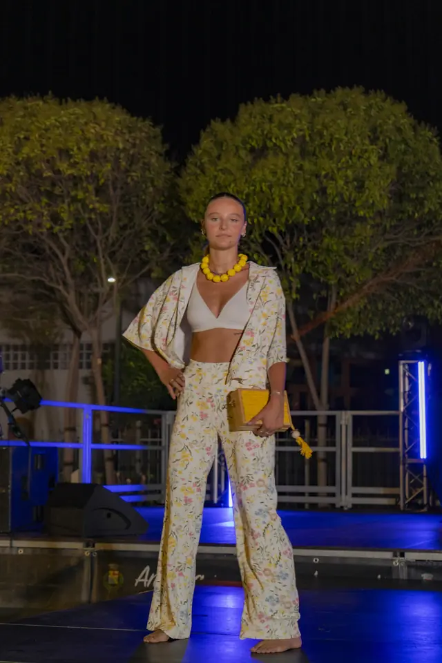 Coppia in passerella, lei in abito nero traforato, lui in camicia a scacchi